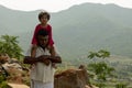 A loving grandfather holds his granddaughter on his shoulder as they walk through a village