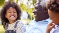 Loving Grandfather Talking With Grandchildren In Garden At Home