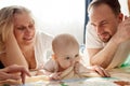 Loving grandma and dad hug and kiss their baby on the floor in the children's room. Happy loving family. Parents and Royalty Free Stock Photo