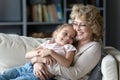 Loving grandmother holds on lap little granddaughter feeling love