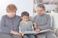 Loving grandparents with grandchild sitting on sofa