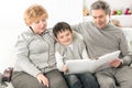 Loving grandparents with grandchild sitting on sofa