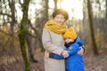 Loving grandson tenderly embracing his joyful elderly grandmother during walking in autumn park. Friendship granny and grandchild