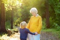 Loving grandson tenderly embracing his joyful elderly grandmother during walking at summer park. Mother`s day holiday