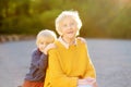 Loving grandson tenderly embracing his joyful elderly grandmother during walking at summer park.