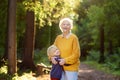 Loving grandson tenderly embracing his joyful elderly grandmother during walking at summer park