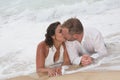 Loving groom kissing bride's mouth on beach