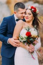 Loving groom kissing his pretty new wife on the cheek in the countryside. Light wind flapping women's hair under stylish