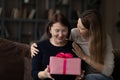 Loving grown-up daughter congratulating mature mother, presenting gift box Royalty Free Stock Photo