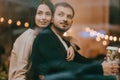 Loving guy and girl sit hugging on the windowsill in a romantic cafe