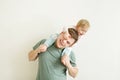 Loving handsome father holding cute baby daughter kid on shoulders over light neutral background