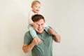 Loving handsome father holding cute baby daughter kid on shoulders over light neutral background