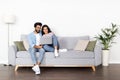 Loving eastern couple sitting on couch at home, using laptop Royalty Free Stock Photo