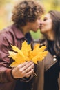 Loving happy couple in autumn in park holding autumn maple leaves in hands. Royalty Free Stock Photo