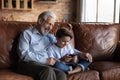 Happy senior grandfather use cellphone with teen grandson