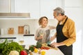 Loving happy senior spouses celebrating marriage anniversary, talking, man making dinner and woman drinking wine Royalty Free Stock Photo