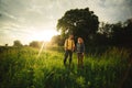 Loving hipster couple walking in the field, kissing and holding hands, hugging, lying in the grass in the summer at sunset. Royalty Free Stock Photo
