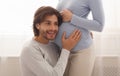 Loving husband listening to his pregnant wife`s belly