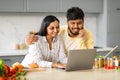 Loving indian couple cooking together, checking recipes on Internet Royalty Free Stock Photo