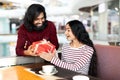 Loving indian guy giving his girlfriend birthday gift at cafe Royalty Free Stock Photo