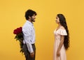 Loving indian guy hiding flowers for his sweetheart behind his back, lover giving his wife roses for Valentine's Day