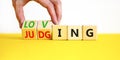 Loving or judging symbol. Concept words Loving or Judging on wooden cubes. Businessman hand. Beautiful yellow table white