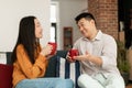 Loving korean couple drinking coffee and talking, enjoying free time together at home, sitting on sofa in living room Royalty Free Stock Photo