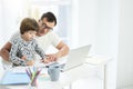 Help your child. Loving latin father playing with his son. Businessman using laptop while working from home and watching Royalty Free Stock Photo