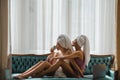 Loving lesbian couple girls drinking coffee embrace on bed. Sexy girlfriends in love at home spend morning together Royalty Free Stock Photo