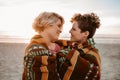 Loving lesbian couple wrapped in a blanket at the beach Royalty Free Stock Photo