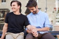 Loving Male Gay Couple Sitting Outside Coffee Shop Holding Hands Royalty Free Stock Photo