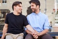 Loving Male Gay Couple Sitting Outside Coffee Shop Holding Hands