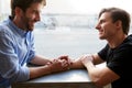 Loving Male Gay Couple Sitting At Table In Coffee Shop Holding Hands Royalty Free Stock Photo