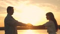 Loving man and woman dance in bright rays of sun on the background of the lake. Young couple dancing at sunset on beach Royalty Free Stock Photo