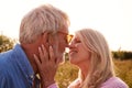 Loving Mature Couple In Countryside About To Kiss Against Flaring Sun Royalty Free Stock Photo