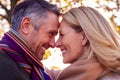 Loving Mature Retired Couple Hugging Against Autumn Countryside With Flaring Sun Royalty Free Stock Photo