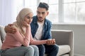 Loving middle-eastern man comforting his depressed wife, home interior Royalty Free Stock Photo