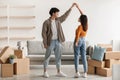 Loving millennial Asian couple dancing in their new home among carton boxes on moving day, copy space Royalty Free Stock Photo