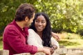 Loving Mixed Race Couple Leaning On Fence On Walk In Countryside