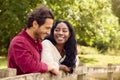 Loving Mixed Race Couple Leaning On Fence On Walk In Countryside