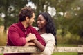 Loving Mixed Race Couple Leaning On Fence On Walk In Countryside