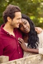 Loving Mixed Race Couple Leaning On Fence On Walk In Countryside