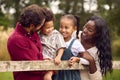 Loving Mixed Race Family Leaning On Fence On Walk In Countryside