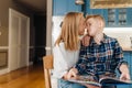 Loving mom kissing her son while reading book together in kitchen Royalty Free Stock Photo