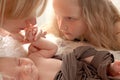 Loving mom and older sister hold the handle of a newborn boy and kiss, cute tiny baby. Portrait a Mom and her baby. Royalty Free Stock Photo