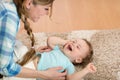 Loving mother tickling her little kid on carpet at home