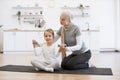 Loving mommy gently stretching daughter& x27;s arms during fitness class at home. Royalty Free Stock Photo
