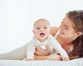 Loving mother and baby bonding at home, playing while relaxing on a bed together. Happy parent being affectionate with Royalty Free Stock Photo