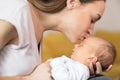 Loving Mother Cuddling Baby Son And Giving Him Kiss On Forehead