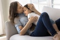 Loving mother kissing cute daughter forehead relaxing together on sofa Royalty Free Stock Photo